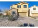 Two-story home with tan exterior, brick driveway and desert landscaping at 8992 Sparkling River Ct, Las Vegas, NV 89178