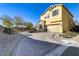 Two-story home with tan exterior, brick driveway and desert landscaping at 8992 Sparkling River Ct, Las Vegas, NV 89178