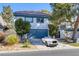 Two-story home boasts a tile roof, tidy landscaping, and a blue garage door, with a luxury car parked in the driveway at 916 Vegas Valley Dr, Las Vegas, NV 89109