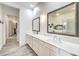 Bright bathroom featuring a double vanity with white countertops and framed mirrors with a glimpse into the closet at 9928 Regency Square Ave, Las Vegas, NV 89148