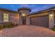Beautiful home exterior featuring professional landscaping, brick driveway and tasteful outdoor lighting at 9928 Regency Square Ave, Las Vegas, NV 89148