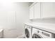 Bright laundry room with white cabinets, washer, and dryer, offering convenient functionality at 9928 Regency Square Ave, Las Vegas, NV 89148