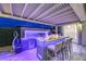 Modern outdoor kitchen with bar seating, built-in grill, and ambient lighting for evening gatherings at 9928 Regency Square Ave, Las Vegas, NV 89148