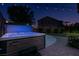 Backyard view showcasing a hot tub, patio, and well-manicured lawn under the soft glow of string lights at 1417 Brushback Ave, Henderson, NV 89074