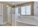 Bathroom featuring a large soaking tub, glass enclosed shower, and a window for natural light at 1417 Brushback Ave, Henderson, NV 89074