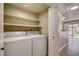 Bright laundry room with white washer, dryer, and shelving for convenient storage space at 1575 W Warm Springs Rd # 413, Henderson, NV 89014