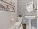 Modern half bathroom featuring tiled accent wall, pedestal sink, and stylish decor at 2910 Raywood Ash Dr, Las Vegas, NV 89138