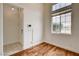 Small room featuring a window with blinds, wood-look floors, white walls, and a peek into the hallway at 3200 Ridgecliff St, Las Vegas, NV 89129