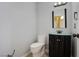 Small bathroom with a toilet, dark vanity, glass sink bowl, and modern mirror at 3953 Broad Meadow Ct, Las Vegas, NV 89129