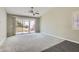Spacious living room featuring neutral colors, a ceiling fan, and sliding glass doors leading to the backyard at 423 Red Canvas Pl, Las Vegas, NV 89144