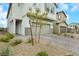Two-story home with tan painted exterior, stone accents, a two-car garage, and a brick driveway at 5016 Kaslo Ave, Las Vegas, NV 89139