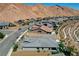 Areal view of a home featuring desert landscaping, mountain views, a manicured lawn with outdoor seating at 54 Mirage View Dr, Henderson, NV 89011