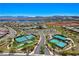 Aerial view of community amenities including tennis courts, pool and clubhouse, with lake and mountain views at 54 Mirage View Dr, Henderson, NV 89011