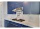 Close-up of a modern kitchen featuring white countertops, blue cabinets, and stainless steel appliances at 54 Mirage View Dr, Henderson, NV 89011