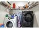 Laundry room with washer, dryer, and metal shelves with various items at 5600 W Bartlett Ave, Las Vegas, NV 89108