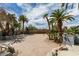 Backyard featuring a sand volleyball court, palm trees, and stone retaining walls at 6520 Turtle Hill Rd, Las Vegas, NV 89110