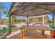 Entertaining backyard featuring a covered patio, wooden picnic table, lush greenery, and a play area at 7902 Jessamy St, North Las Vegas, NV 89084