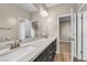 A neutral primary bathroom with a double vanity, chrome faucets, dark cabinets, and entry to another room at 9091 Becket Ranch Ct, Las Vegas, NV 89113