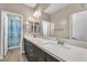 Neutral primary bathroom with double sinks, chrome faucets, dark cabinets, and entry to the bath/shower room at 9091 Becket Ranch Ct, Las Vegas, NV 89113