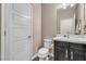 A neutral powder room with modern vanity, white toilet, decorative mirror and white paneled door at 9091 Becket Ranch Ct, Las Vegas, NV 89113