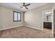 A bedroom with carpet, neutral walls, ceiling fan and a door to the ensuite bathroom with tile floors and dark cabinets at 9091 Becket Ranch Ct, Las Vegas, NV 89113