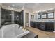 Luxurious main bathroom features a soaking tub, dark cabinets, granite counters and tiled floors at 9091 Becket Ranch Ct, Las Vegas, NV 89113