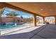 A covered patio overlooks a serene pool and landscaped backyard, providing an ideal space for outdoor relaxation at 9091 Becket Ranch Ct, Las Vegas, NV 89113