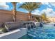 Inground pool boasting stone water feature, lush plantings and blue skies at 9091 Becket Ranch Ct, Las Vegas, NV 89113