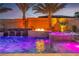 Nighttime view of a pool and spa with waterfall feature, color lights, and fire bowls for a relaxing ambiance at 9091 Becket Ranch Ct, Las Vegas, NV 89113