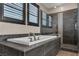 Main bathroom featuring black tiled soaking tub with silver hardware and glass enclosed shower at 9091 Becket Ranch Ct, Las Vegas, NV 89113