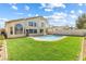 Spacious backyard with a refreshing pool, lush lawn, and mature trees under a sunny sky at 9916 Dusty Winds Ave, Las Vegas, NV 89117