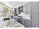 Modern kitchen featuring gray cabinets, stainless appliances, white backsplash, granite counters and a kitchen island at 9916 Dusty Winds Ave, Las Vegas, NV 89117