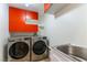 Convenient laundry room featuring modern washer and dryer with bright orange cabinets at 10381 Walking View Ct, Las Vegas, NV 89135