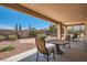 Relaxing covered patio with stone table, chairs, and a landscaped yard at 10547 Grazia Ave, Las Vegas, NV 89135