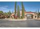 Elegant gated community entrance with tall Cypress trees, lush greenery, and a terracotta tiled roof at 10547 Grazia Ave, Las Vegas, NV 89135