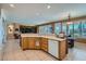 Open concept kitchen with breakfast bar, oak cabinets, tile floors, and access to the living area at 10547 Grazia Ave, Las Vegas, NV 89135