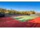 Well-maintained tennis court with vibrant colors and a backdrop of lush greenery at 10547 Grazia Ave, Las Vegas, NV 89135