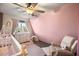 Cute bedroom with crib, neutral chair, pastel pink walls and a beautiful view from the window at 11875 Maggie Ave, Las Vegas, NV 89166