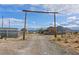 Gravel driveway leading to a ranch-style home under a rustic wooden archway with mountain views at 11875 Maggie Ave, Las Vegas, NV 89166