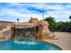 Backyard with rock waterfall feature and outdoor seating area at 4578 Churchfield Cir, Las Vegas, NV 89103