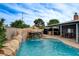 Backyard pool featuring rock waterfall and slide with covered patio and outdoor seating at 4578 Churchfield Cir, Las Vegas, NV 89103