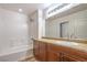 Clean bathroom with a vanity, bathtub, tile surround, and large mirror at 10085 S Riley St, Las Vegas, NV 89178