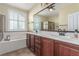 Bathroom with dual sinks, dark cabinetry, and soaking tub at 2489 Black River Falls Dr, Henderson, NV 89044