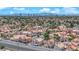Expansive aerial view of a neighborhood with lush landscaping, tile roofs, and a backdrop of mountains and city skyline at 6536 Castor Tree Way, Las Vegas, NV 89108