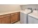 Well-lit laundry room with a side-by-side washer and dryer, plus ample cabinet storage at 89 Oratorio Dr, Henderson, NV 89015