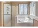 Bright bathroom featuring a glass enclosed shower and a large soaking tub under a window at 8942 Galena Crossing St, Las Vegas, NV 89123
