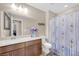 Bright bathroom features a vanity, a decorative mirror, and a shower with a floral curtain at 9981 Sable Point St, Las Vegas, NV 89178