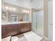 Bathroom featuring a double sink vanity with dark wood cabinets, a large mirror, and a glass-enclosed shower, providing a spa-like experience at 9981 Sable Point St, Las Vegas, NV 89178