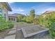 Spacious backyard with a stone fire pit area, lush greenery, and mature trees offering a tranquil setting at 10150 Emerald Sunset Ct, Las Vegas, NV 89148