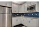 Well-lit kitchen with stainless steel appliances, white cabinets, and stylish blue backsplash at 10172 Fire Skye Ave, Las Vegas, NV 89166